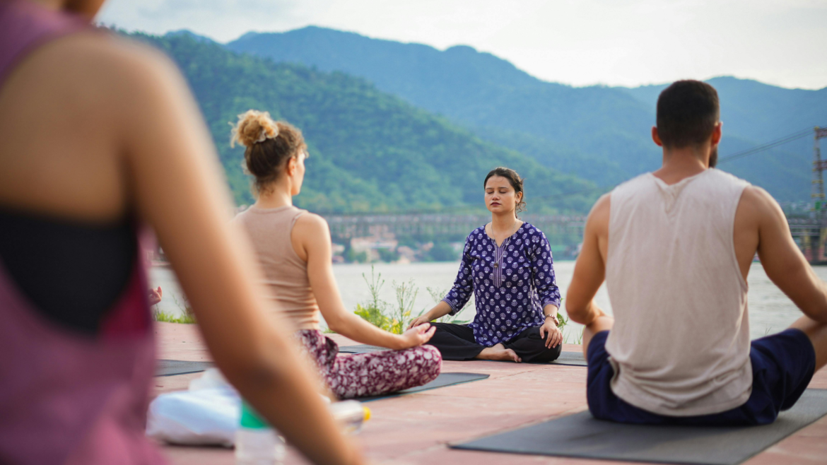 A meditation class sits by the Ganga in Rishikesh, Uttarakhand